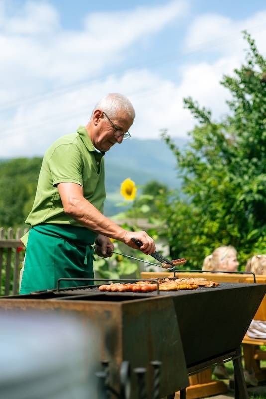 Älterer Herr beim Grille in Garten