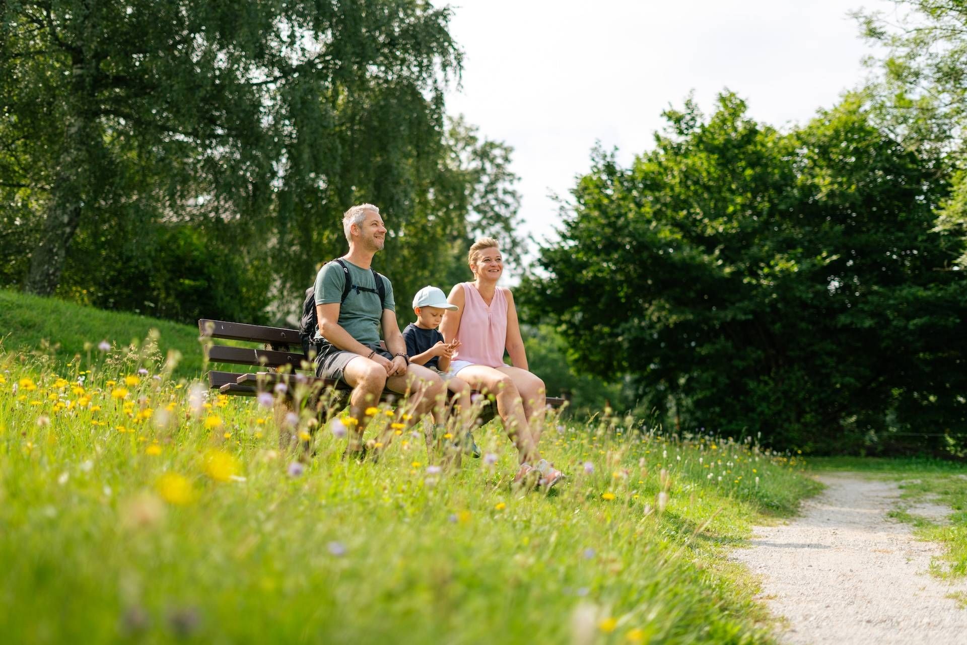 Familie sitzt auf einer Bank beim Wandern