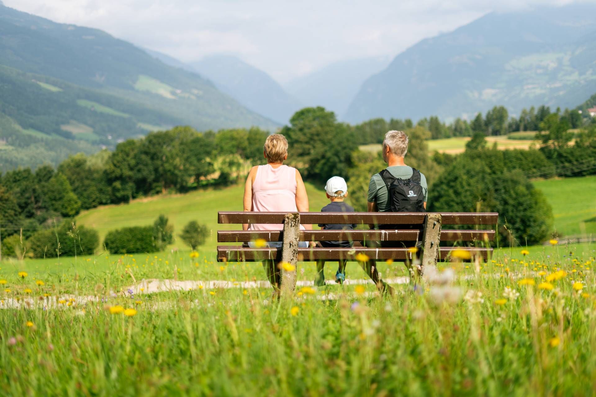 Familie sitzt auf einer Bank und blickt auf die Berge